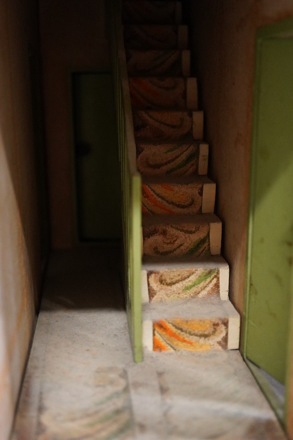 A 1920s/30s commercially produced dolls house, possibly by Tri-ang, of plywood construction, overlaid with printed paper roof tiles and brickwork, and tinplate windows and window frames, comprising of four rooms with bay